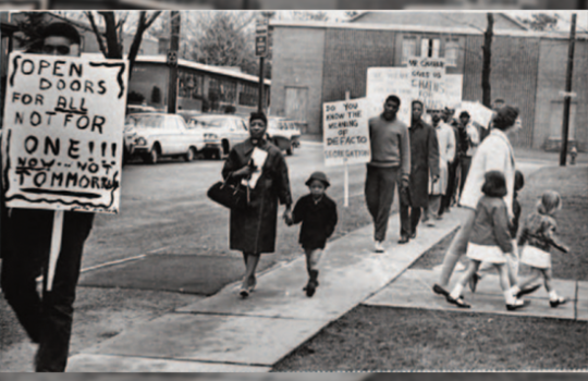 Outside Hartford's Noah Webster Elementary School, people protest against neighborhood school zones that created school segregation. 1964, uncredited, Hartford Public Library.